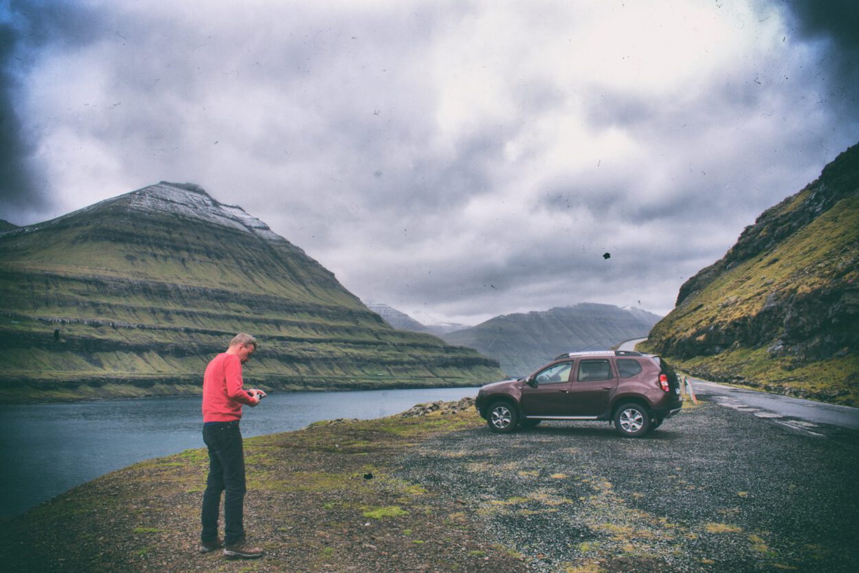 Ein Mann steht neben einem Auto auf einer Straße in Island.