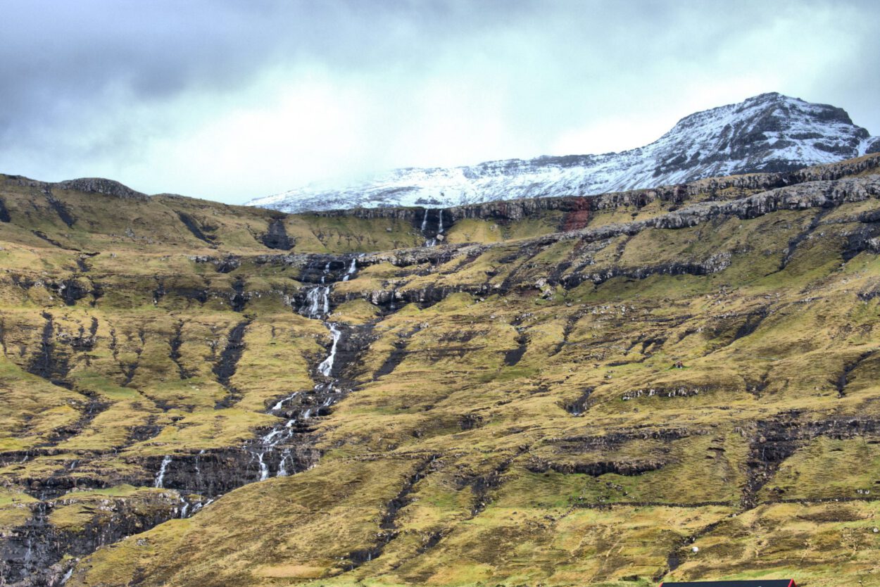 Ein Zug, der einen Berg hinunterfährt, mit einem Wasserfall im Hintergrund.