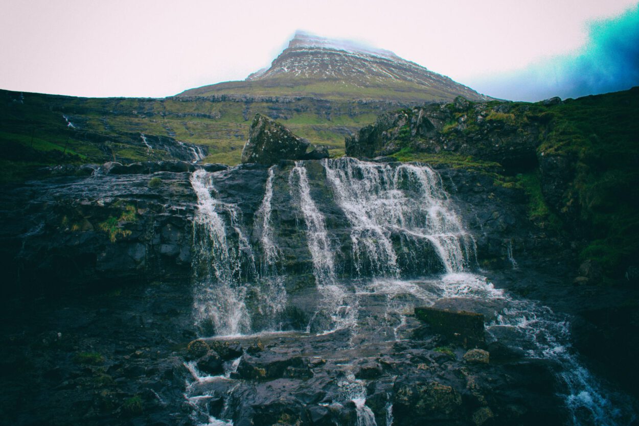 Ein Wasserfall in Island mit einem Berg im Hintergrund.