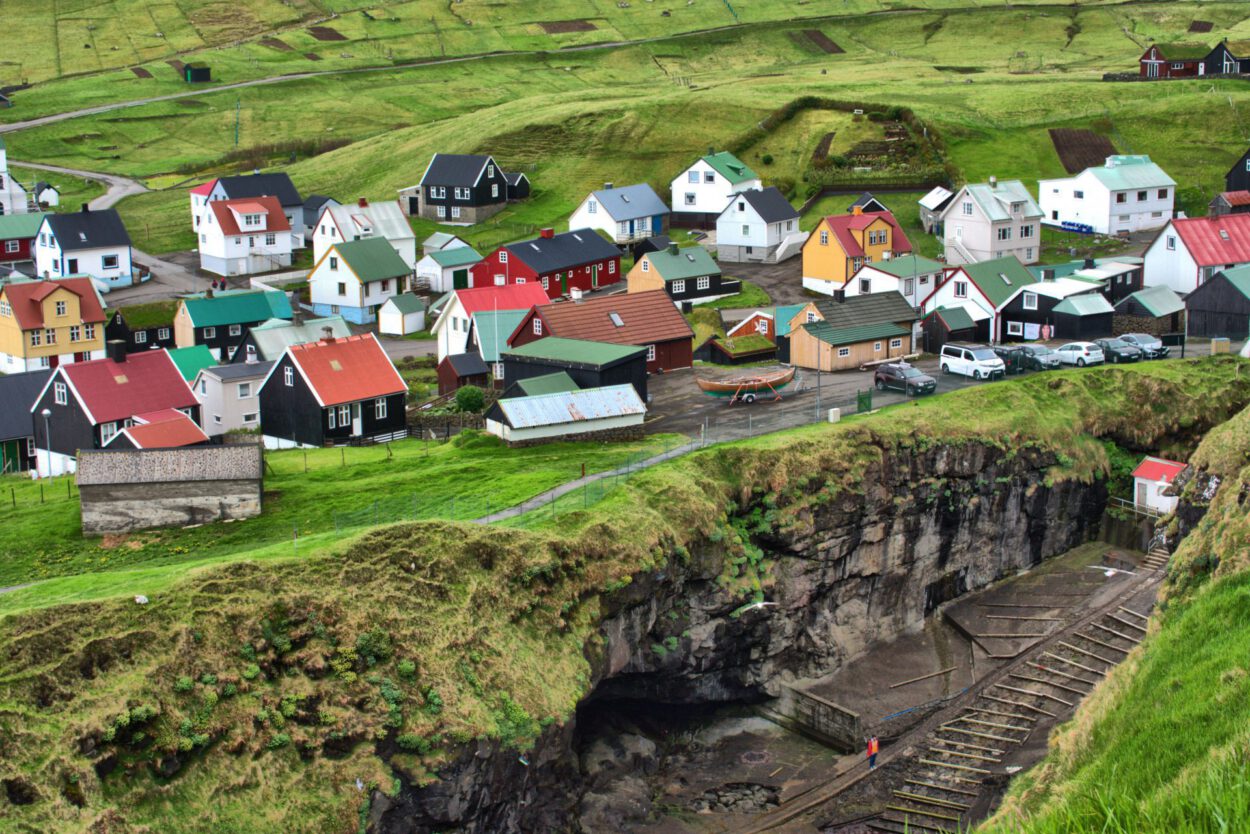 Auf einer Klippe liegt ein Dorf mit bunten Häusern.