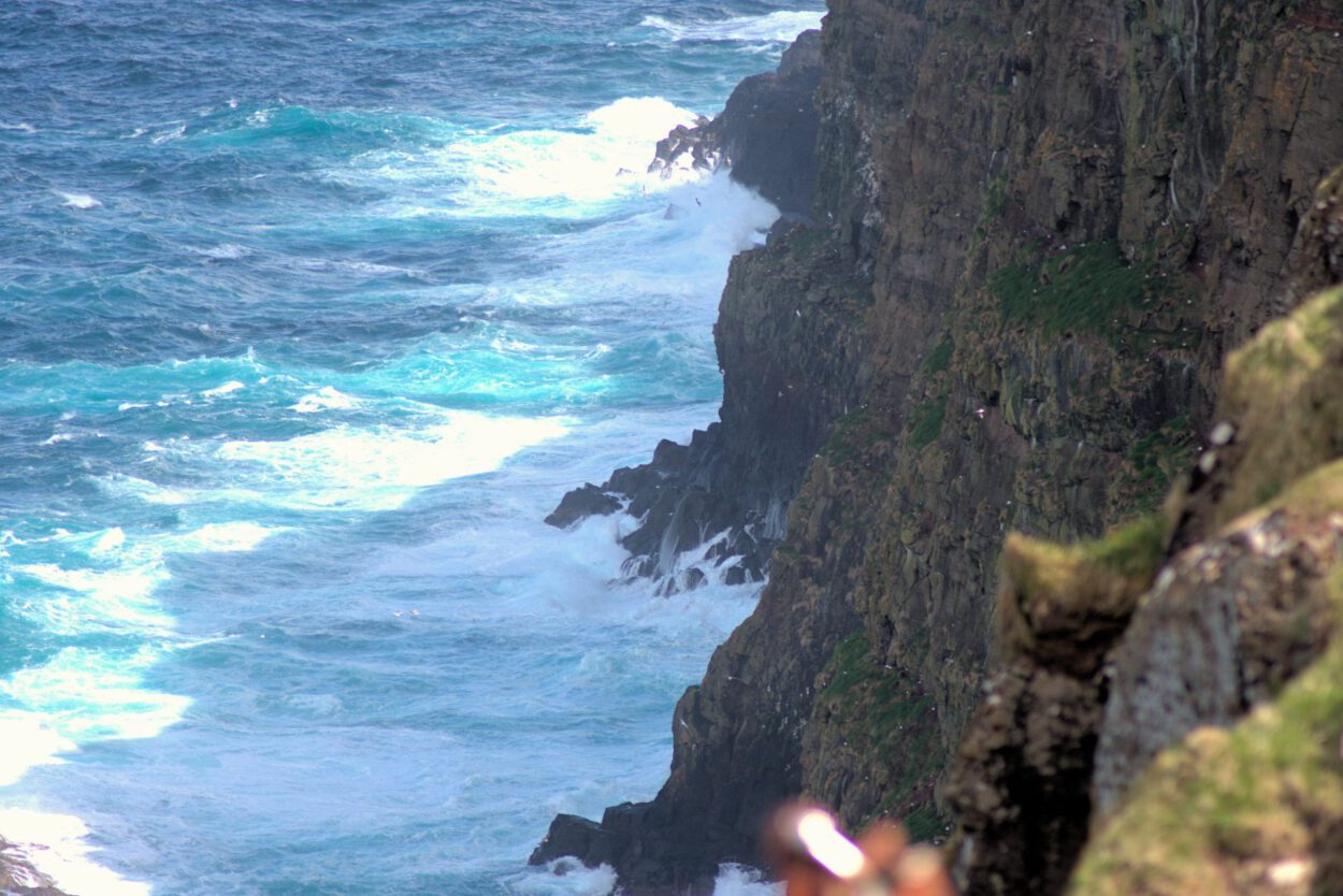 Ein Mann steht auf einer Klippe mit Blick auf den Ozean.