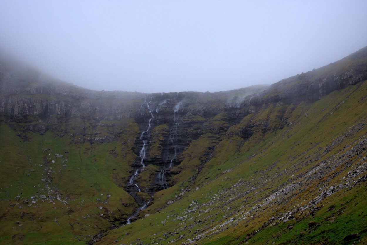 Ein Wasserfall inmitten eines grasbewachsenen Hügels.