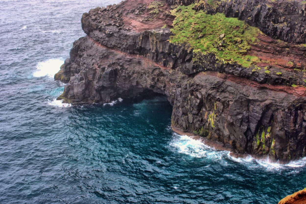 Eine Klippe mit einem Loch in der Nähe des Ozeans.