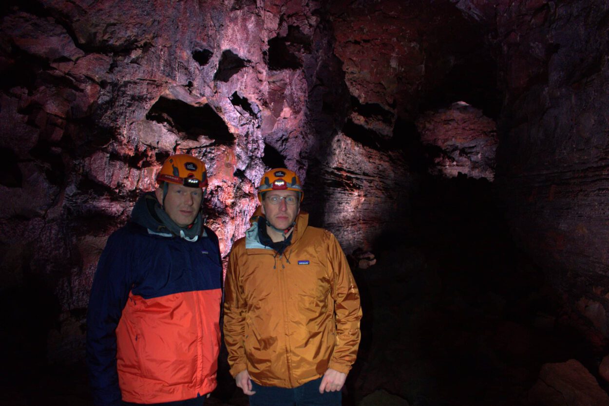 Zwei Männer stehen vor einer Höhle.