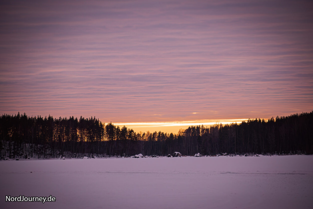Ein schneebedecktes Feld bei Sonnenuntergang.