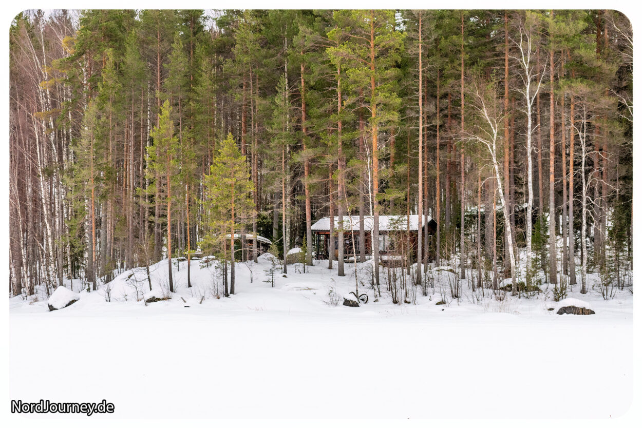 Eine Hütte, umgeben von Bäumen im Schnee.