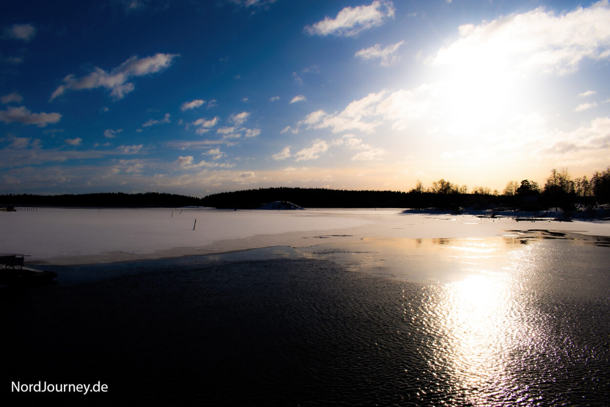 Die Sonne scheint auf einen zugefrorenen See.