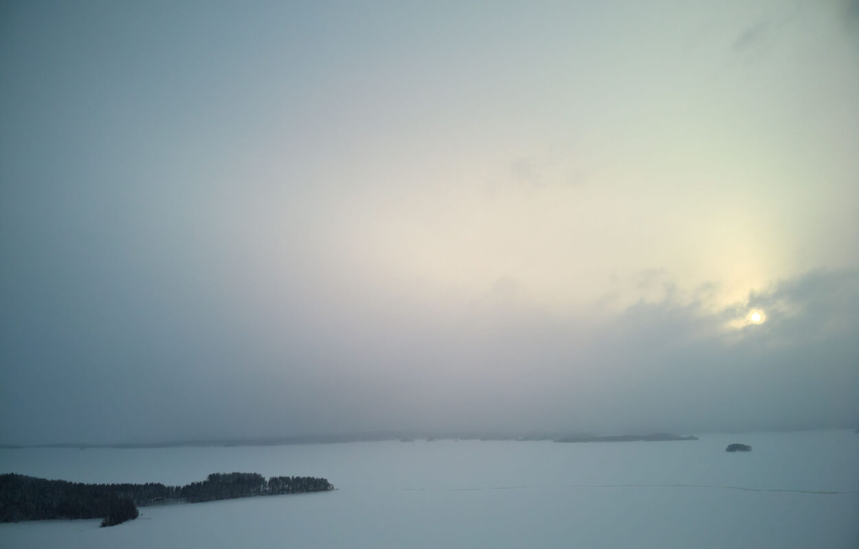 Die Sonne geht über einem schneebedeckten See auf.